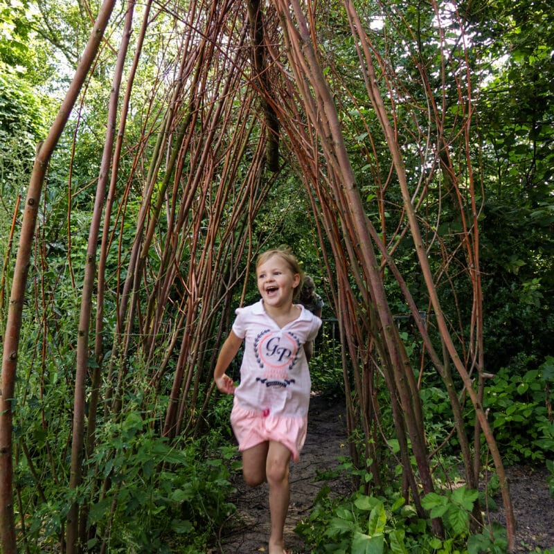 Meisje rent door wilgenhut