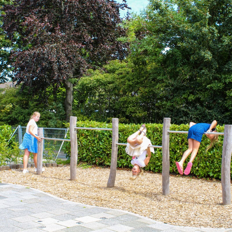 Kinderen bij duikelrekken op kleuterplein